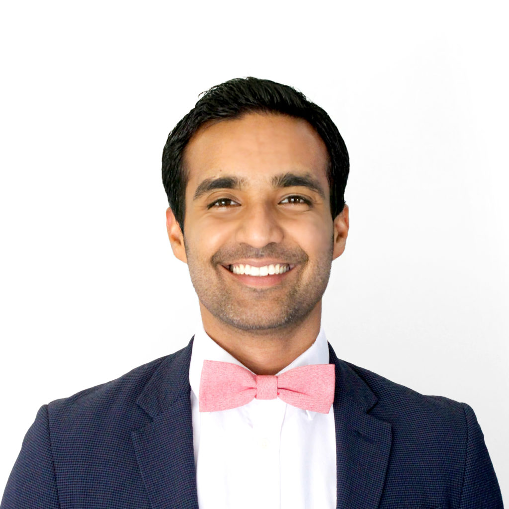 A young professional man wearing a suit jacket and pink bow tie. 